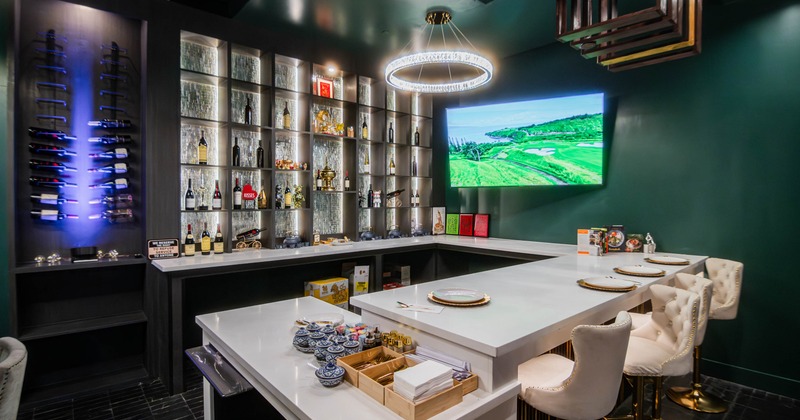 Interior,  bar with white countertops, beige chairs, wine rack, shelves, and a TV