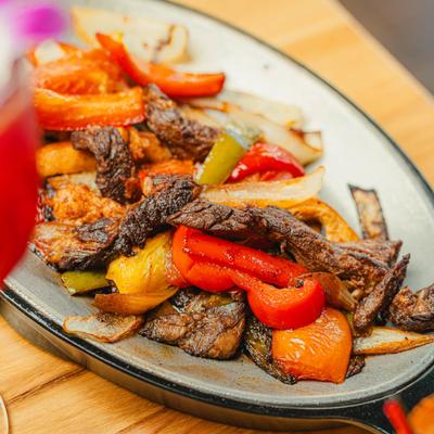 Steak and chicken fajitas with peppers and onions.
