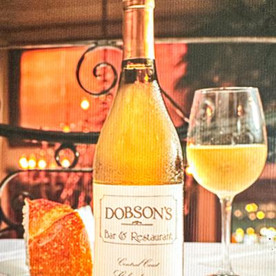 A branded bottle of white wine beside a glass of white wine