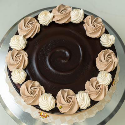 Chocolate cake topped with glossy ganache and a border of piped rosettes.
