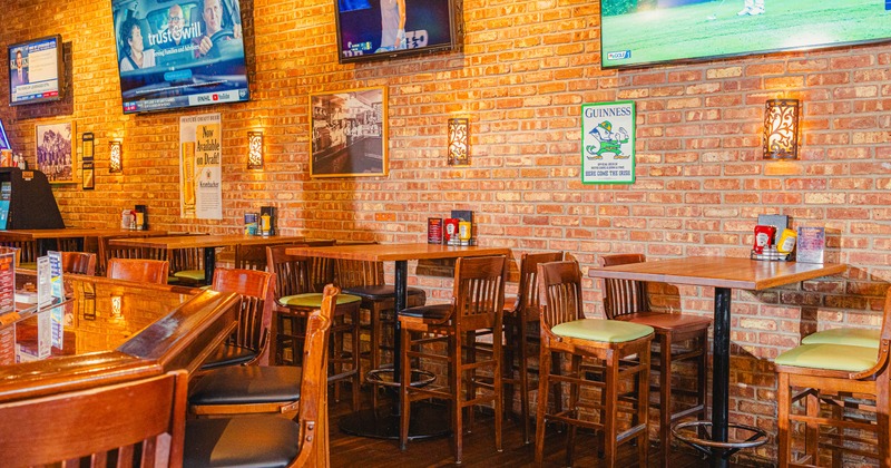 Interior of a bar with televisions, wooden tables, and chairs