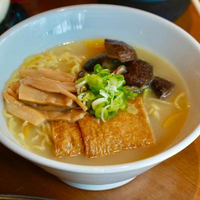 A bowl of ramen soup topped with mushrooms, bamboo shoots, and green onions.