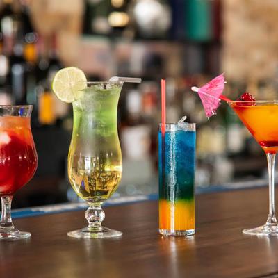 Various cocktail drinks lined up on a bar counter.