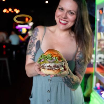 A smiling guest holding a burger in their hands.