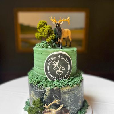 A two-tiered hunting-themed cake featuring green frosting.