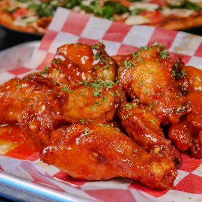 Sauced chicken wings with herb garnish served on checkered paper.