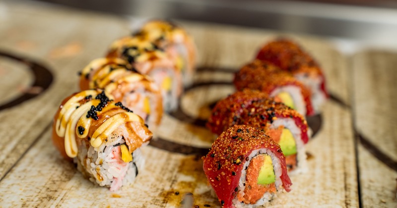 Two distinct rows of gourmet sushi rolls sit beautifully arranged on platter
