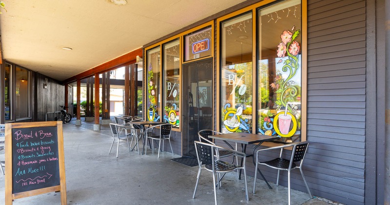 Outdoor seating area of a café with colorful window paintings