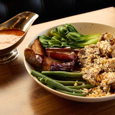 Asian dish with bok choy, eggplant, green beans, and beef topped with peanuts.
