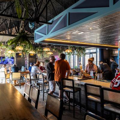 Bar area with hanging greenery and guests standing at the counter.