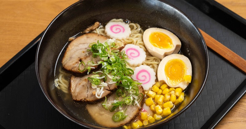 Ramen topped with sliced pork, soft-boiled eggs, sweet corn and narutomaki