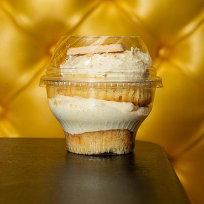 Banana pudding dessert cup served on a dark table with yellow seating backdrop.