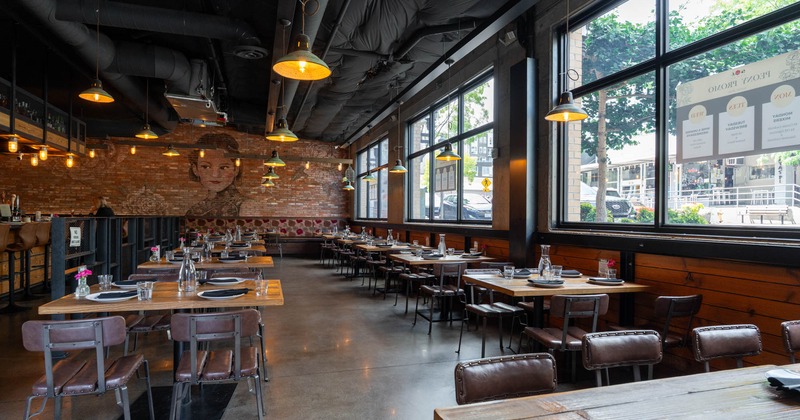 Interior, seating area, tables and chairs ready for guests, concrete flooring, large windows