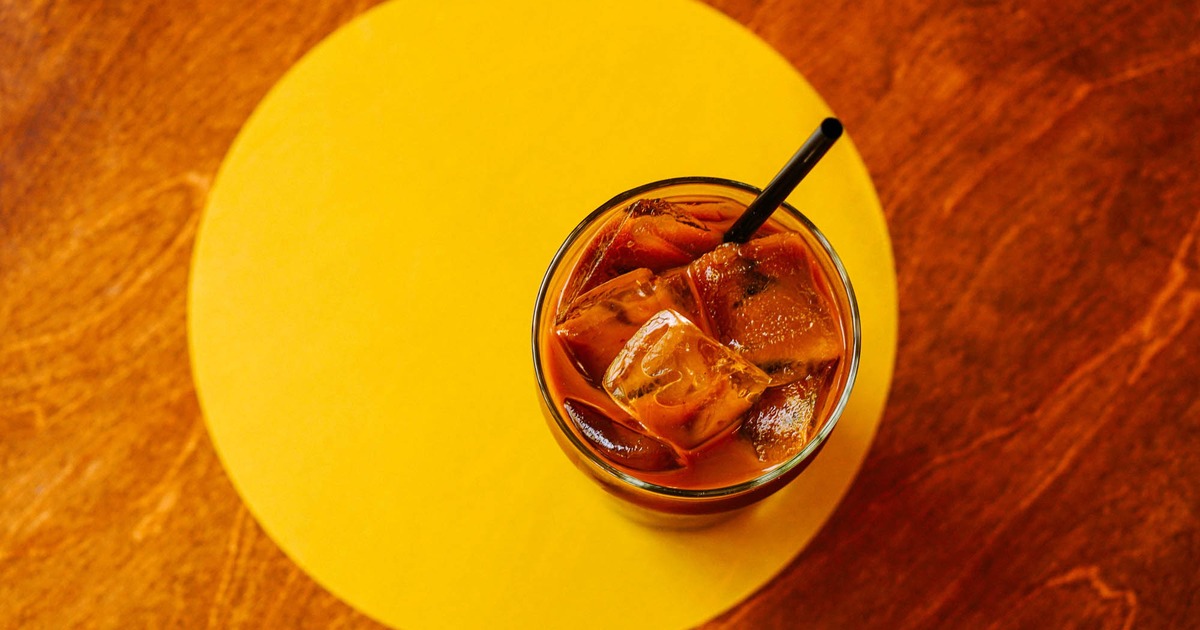 Iced drink with a black straw on a yellow coaster