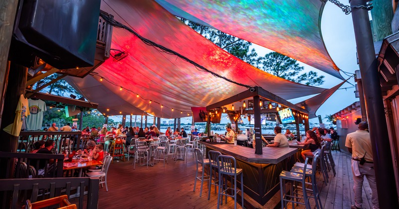 Outdoor patio area with awnings, string lights, table seating and a bar counter