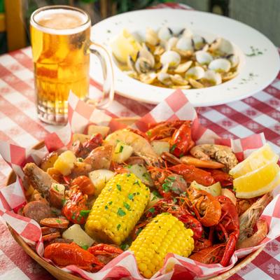Seafood boil with crawfish, shrimp, sausage, corn, and potatoes served with a beer.