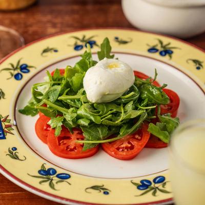 A colorful salad with tomatoes, greens, and burrata cheese.