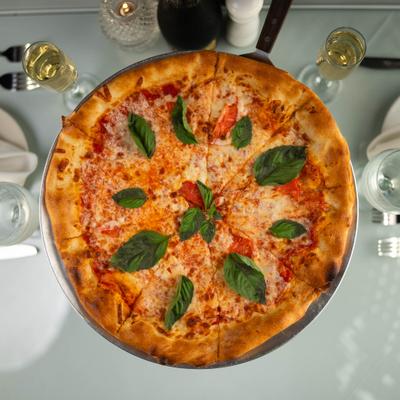 Large margherita pizza topped with fresh basil leaves.
