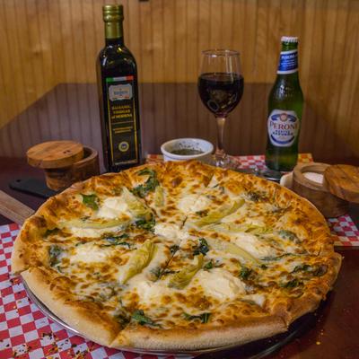 Spinach and artichoke pizza served with drinks and condiments.