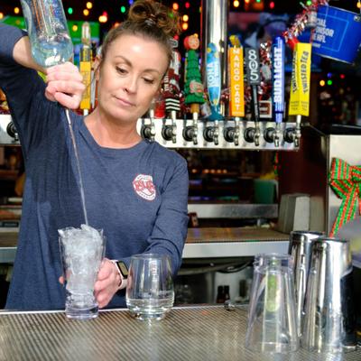 Bartender free pouring spirit from the bottle into a glass with ice.