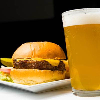 Cheeseburger served on the table with a glass of beer.