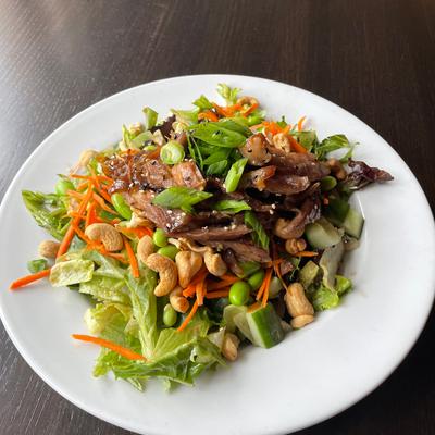Crispy duck salad, with lettuce, almonds, shredded carrots, cucumber, and sesame seeds