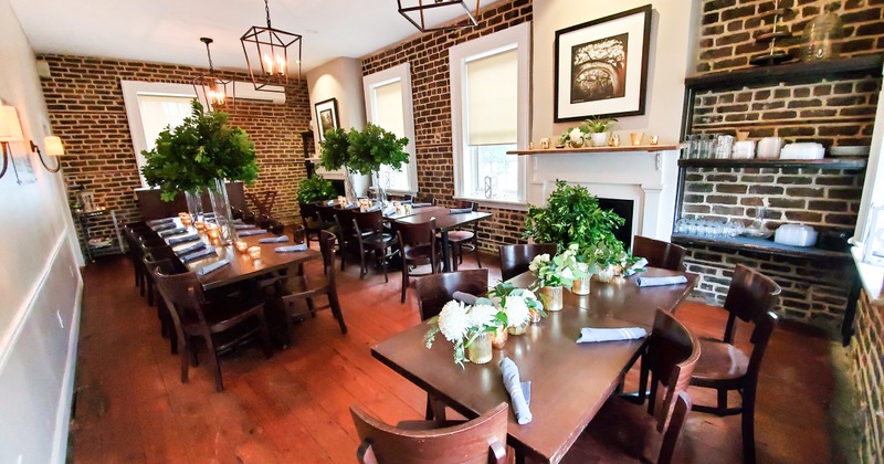 Dining room with wooden tables, exposed brick walls, and decorative plants