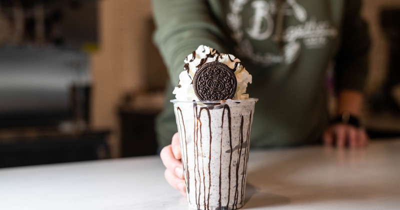 hand passing a milkshake