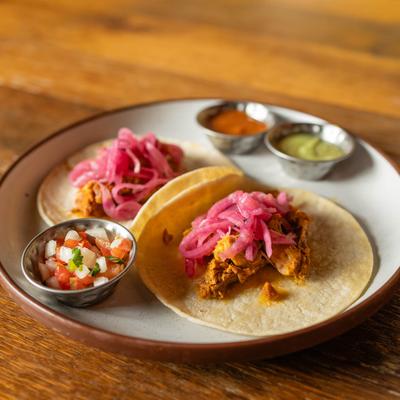 Pulled pork tacos, with pickled red onions, served with pico de gallo, and sauces.