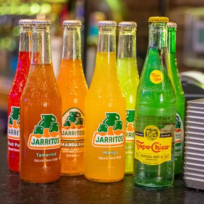 Colorful bottles of Mexican sodas on a counter.