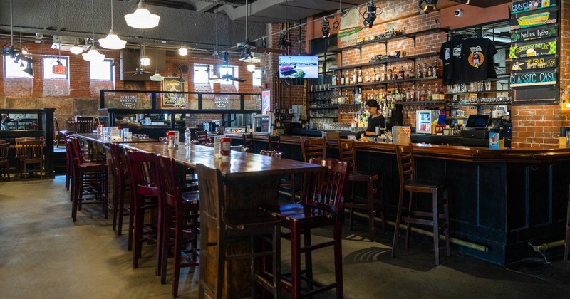 Interior, high seating area, high wooden top tables with stools, bar on the right