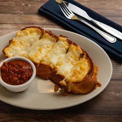 Cheesy bread on white plate with side of tomato sauce.