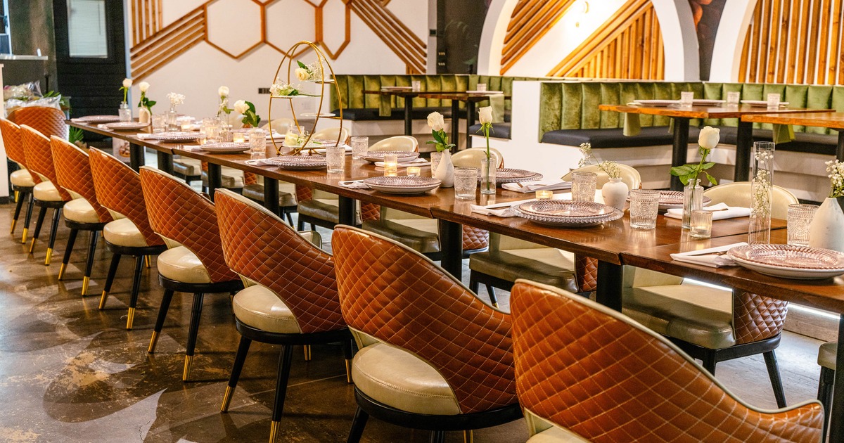 Interior -  a long, elegantly set dining table, quilted chairs and geometric wall patterns.