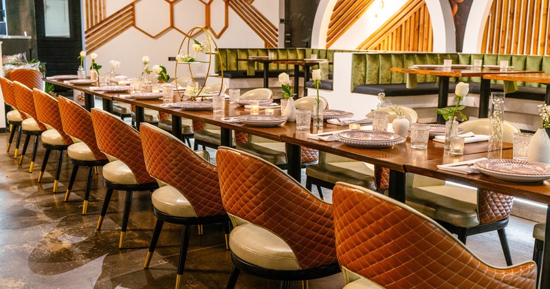 Interior -  a long, elegantly set dining table, quilted chairs and geometric wall patterns.
