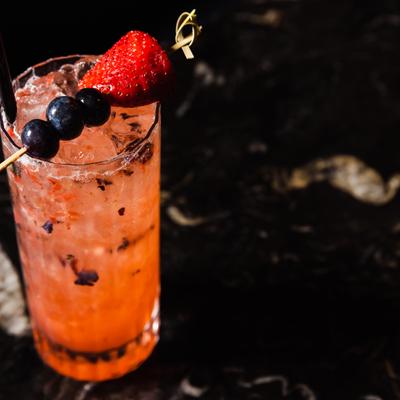 Orange cocktail with strawberry and blueberry garnish