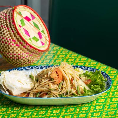Lao Papaya Salad on a table with a green-yellow tablecloth.