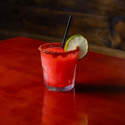 Red cocktail with a spiced rim and a lime wheel.