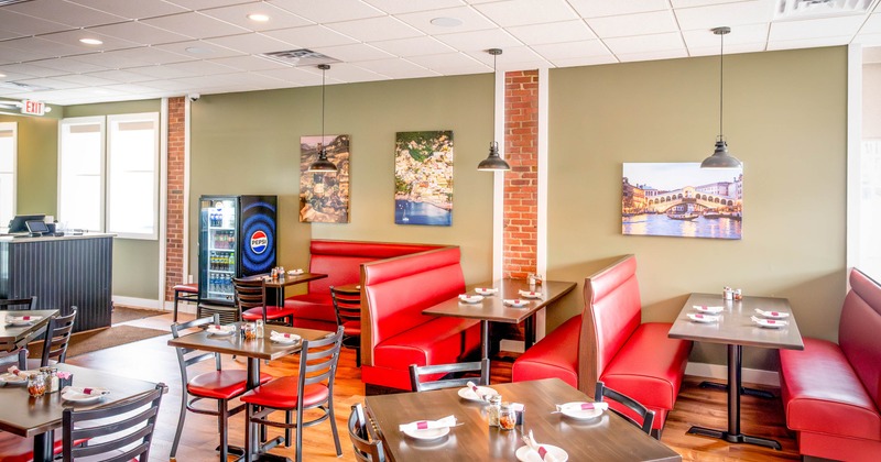 Modern restaurant interior with red seating and scenic wall art.