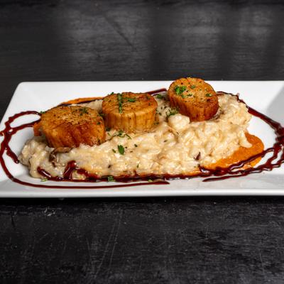 Pan-seared scallops on a bed of truffle mushroom risotto and romesco sauce.