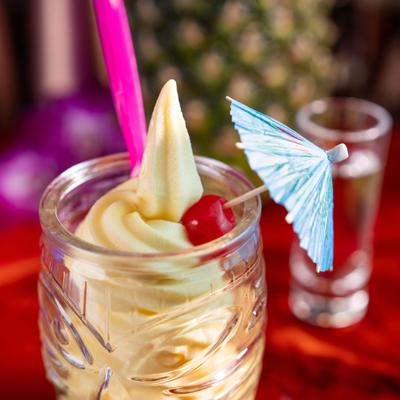 Pineapple frozen yogurt in a tiki glass, garnished with a cherry and an umbrella.