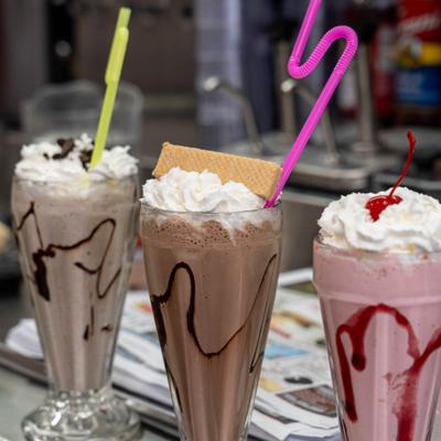 Three milkshakes with whipped cream and toppings.