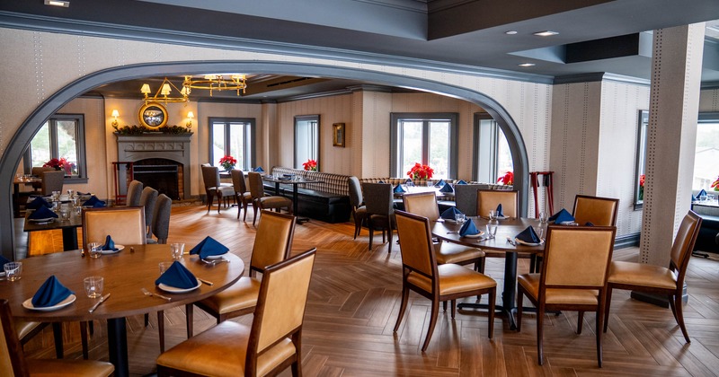Interior dining area with wooden tables and chairs, plants, and a fireplace
