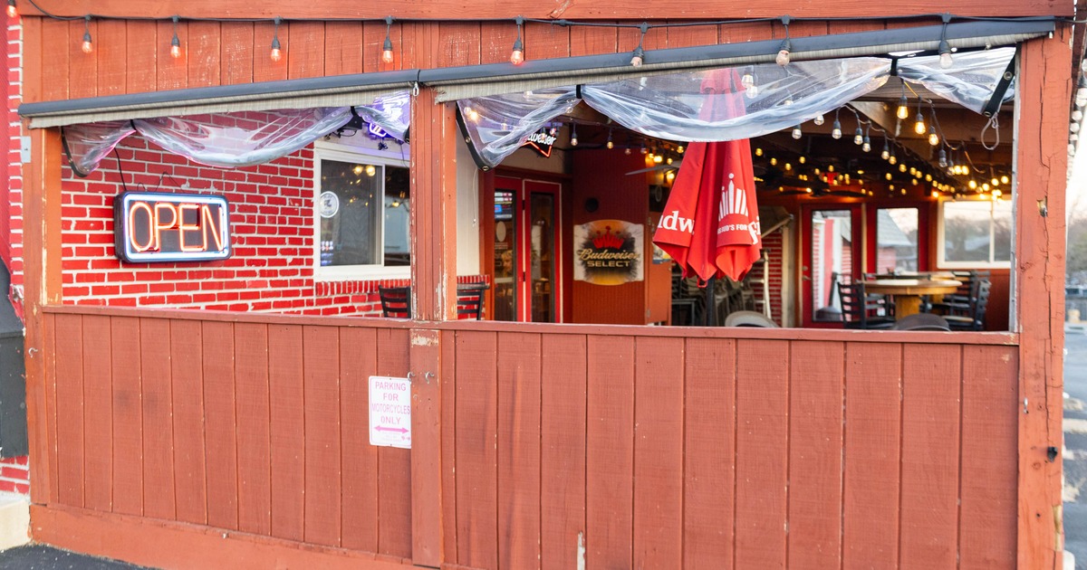 Covered outdoor patio area with a red wooden fence and string lights