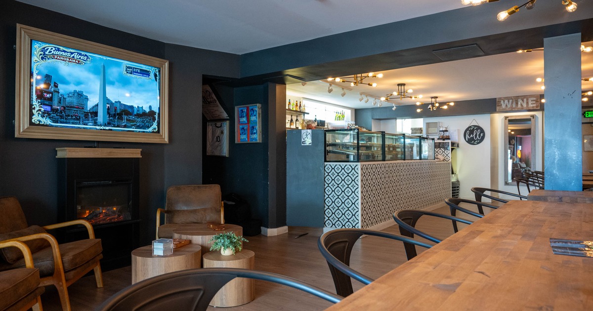 A chic cafe interior with a digital screen, fireplace, seating area and a patterned counter.