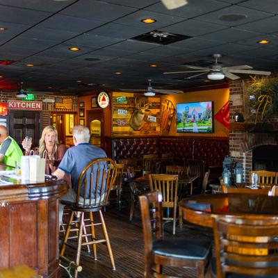 Pub interior with a wooden bar, leather seating, and vintage wall decor.