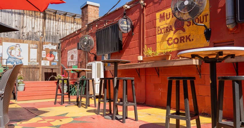 Exterior, high seating tables with stools, partially covered seating area, fans