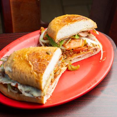 Torta Cubana sandwich cut in half on a red plate.