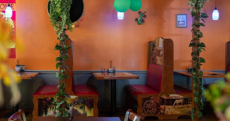 Interior of a colorful restaurant with orange walls, decorated booths, and indoor plants