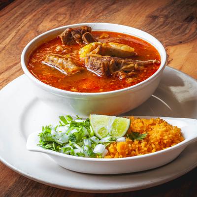 Caldo De Res served with sides of rice, chopped onion and cilantro.