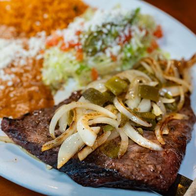 Grilled flank steak, with guacamole, onions, rice, and refried beans.